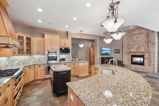 The gourmet kitchen shines with granite counters, slate flooring, a hearth room, and a large breakfast bar that opens to the informal dining area and screen porch.