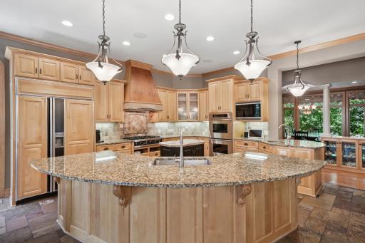 The gourmet kitchen shines with granite counters, slate flooring, a hearth room, and a large breakfast bar that opens to the informal dining area and screen porch.
