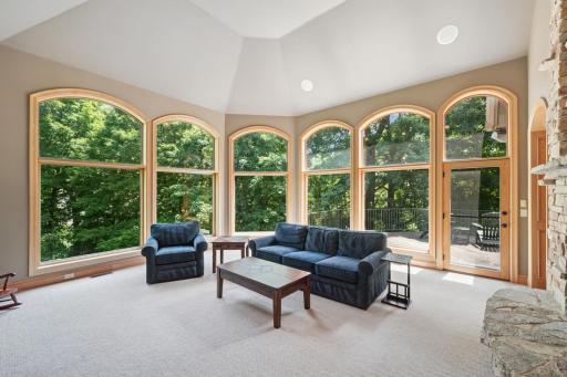The great room features a soaring ceiling, floor-to-ceiling stone fireplace, and expansive windows that bring in stunning natural views.