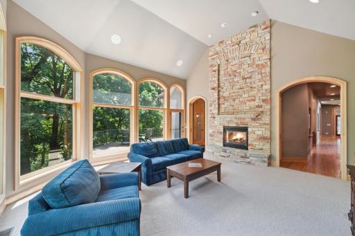 The great room features a soaring ceiling, floor-to-ceiling stone fireplace, and expansive windows that bring in stunning natural views.
