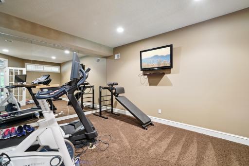 Private home gym featuring double-door entry and a full mirrored wall for the ultimate workout experience.