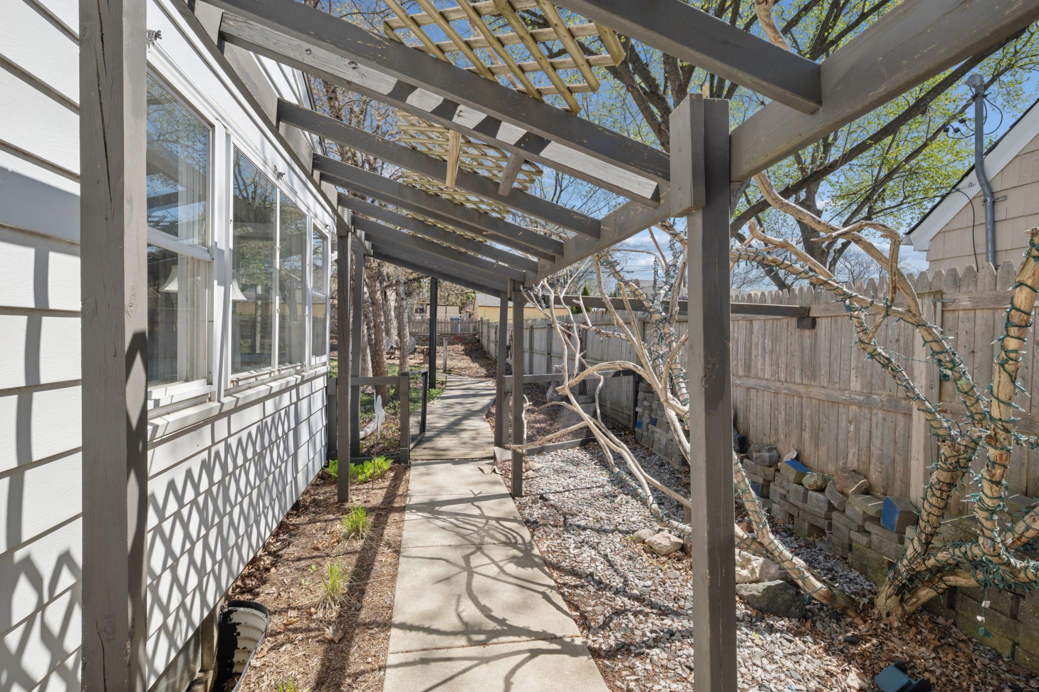 Stroll down the concrete sidewalk with arbor that leads to the picturesque backyard.