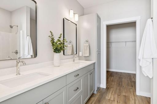 Private primary features a dual sink vanity and walk-in closet and shower