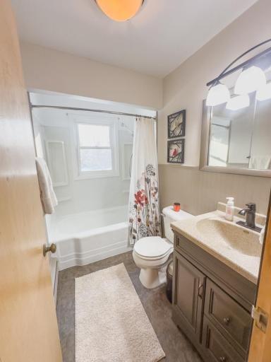 Full bathroom featuring a tub/shower combination, vanity with storage, and overhead lighting.