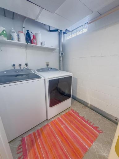 Dedicated laundry area with washer and dryer hookups and shelving for supplies.