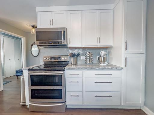 Kitchen view highlighting stainless steel range, microwave, tiled backsplash, and ample cabinet storage.