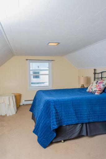 Carpeted bedroom with sloped ceilings, neutral finishes, and window for natural light.