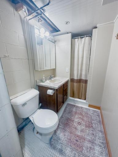 Bathroom featuring a vanity sink, toilet, and shower with curtain enclosure.