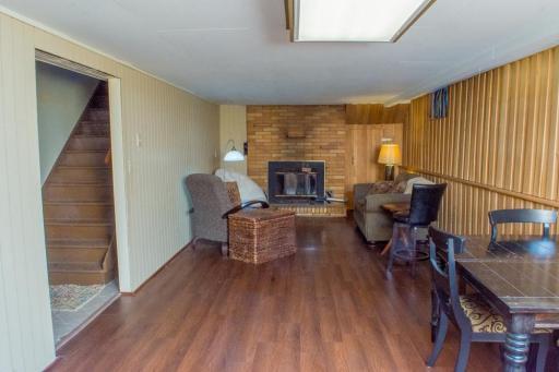 Finished lower-level living area featuring wood-style flooring, a brick fireplace, and flexible seating space.