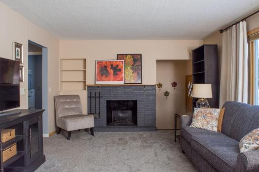 Living room view showcasing a central fireplace, built-in shelving, and adjacent openings to other areas.