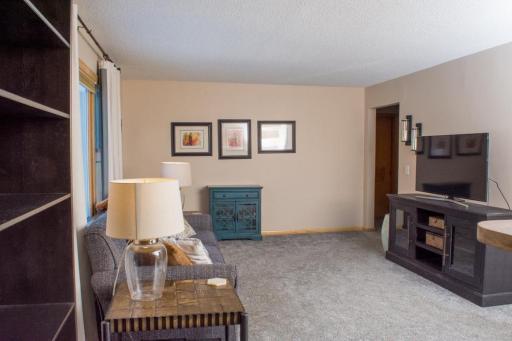Main-level living area with carpeted flooring, built-in shelving, and space for seating and media.