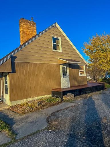 2. **Side Exterior** – Side elevation featuring low-maintenance siding and deck access, with paved driveway nearby.