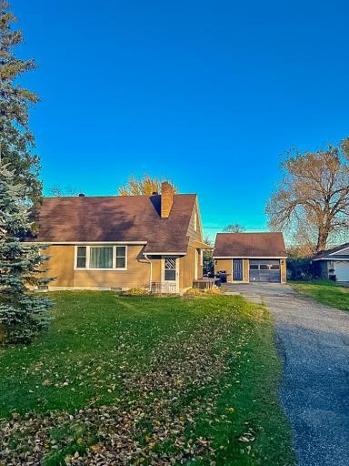 **Front Exterior** – Front façade with mature landscaping, sloped roofline, and large front window allowing natural light into the interior.