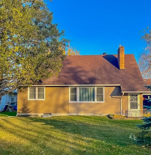**Front Exterior** – Front façade with mature landscaping, sloped roofline, and large front window allowing natural light into the interior.