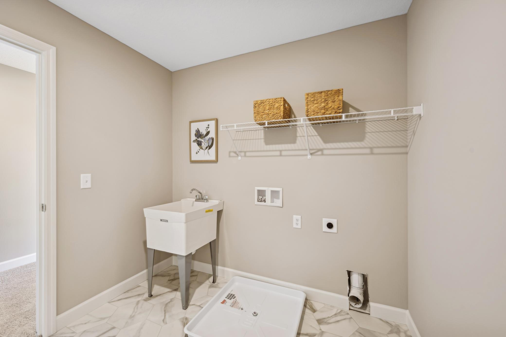 Laundry off primary suite. Photos taken from a former model, talk with sales agent about finishes going into home.