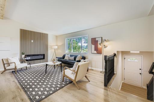 Airy living room with vaulted ceiling, modern electric fireplace, and statement wood beam. Enjoy unobstructed views of the park — no houses across the street!