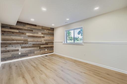 Lower-level family room with wood accent wall, recessed lighting, and bonus under stairs storage.