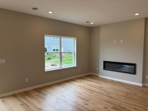 The spacious living room with huge windows and a cozy fireplace awaits you.