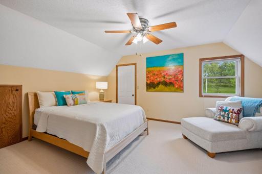 The spacious upper-level bedroom offers a cozy sitting area and a generous closet, making it a perfect retreat for guests.