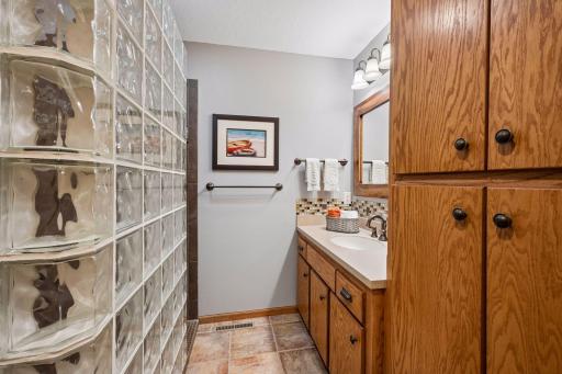 Beautifully updated main-level bath features a walk-in glass block shower, custom tile accents, and abundant storage.
