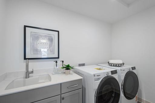 Upper-level laundry room with cabinetry and sink