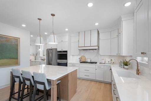 ELITE kitchen + prep kitchen with floor to ceiling cabinetry, double ovens, gas range, built-in hood vent, quartz countertops extended up backsplash, 2 sinks, upgraded appliances