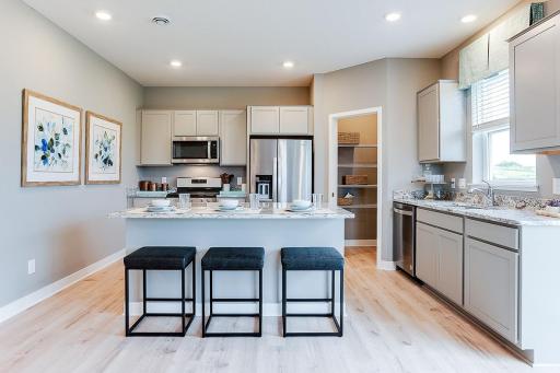 Stunning AND functional all in one, as the kitchen space features a pantry closet for help with storage - and an oversized island coated in granite with an overhang for seating!