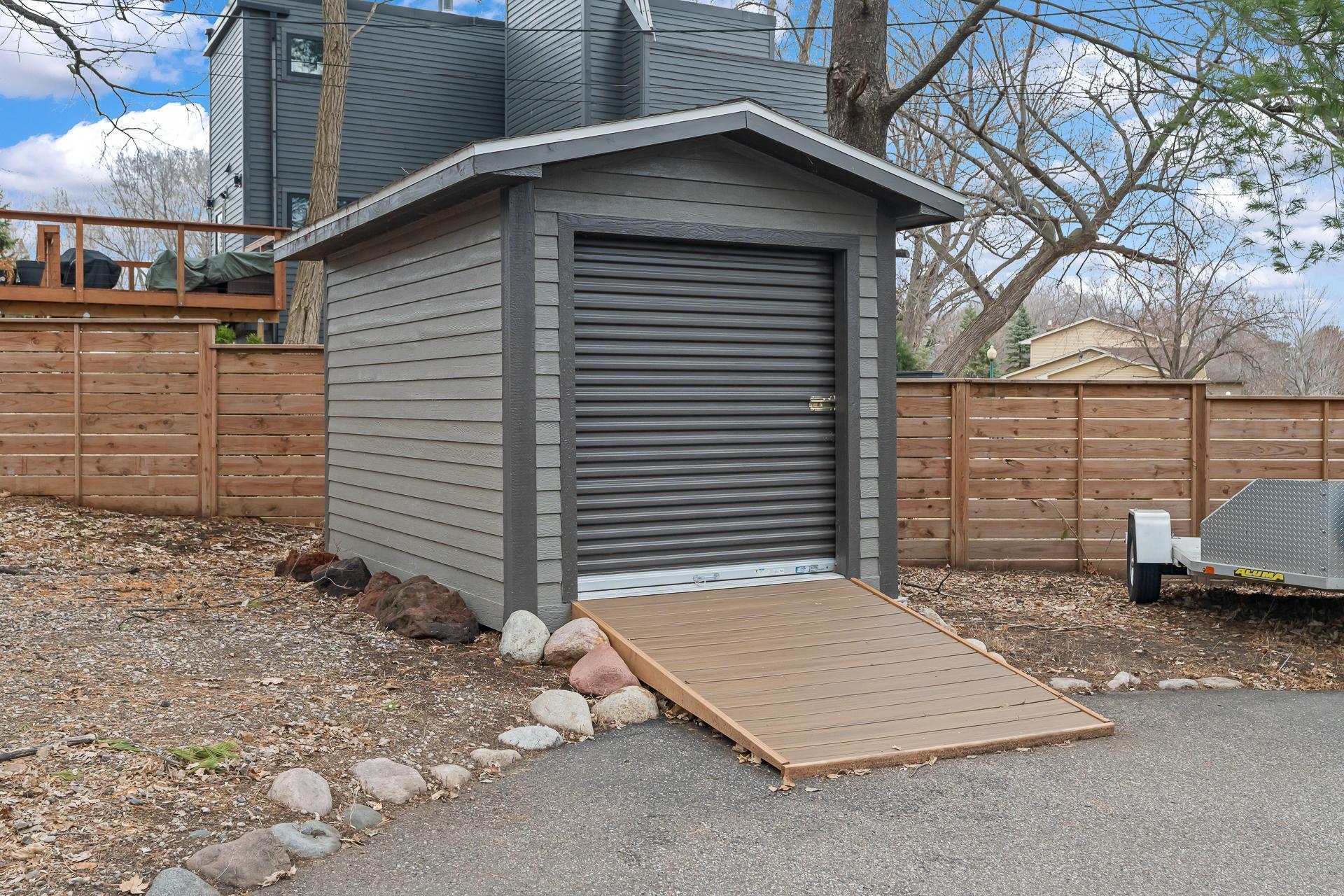 Wired storage shed with roll up garage door, lighting, and ramp.