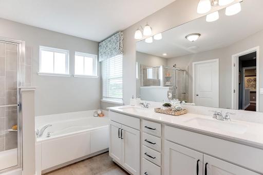 An extension of the primary suite, this private and spacious bathroom contains a double-vanity, a separate shower and tub, a private water closet, plus two walk-in closets.