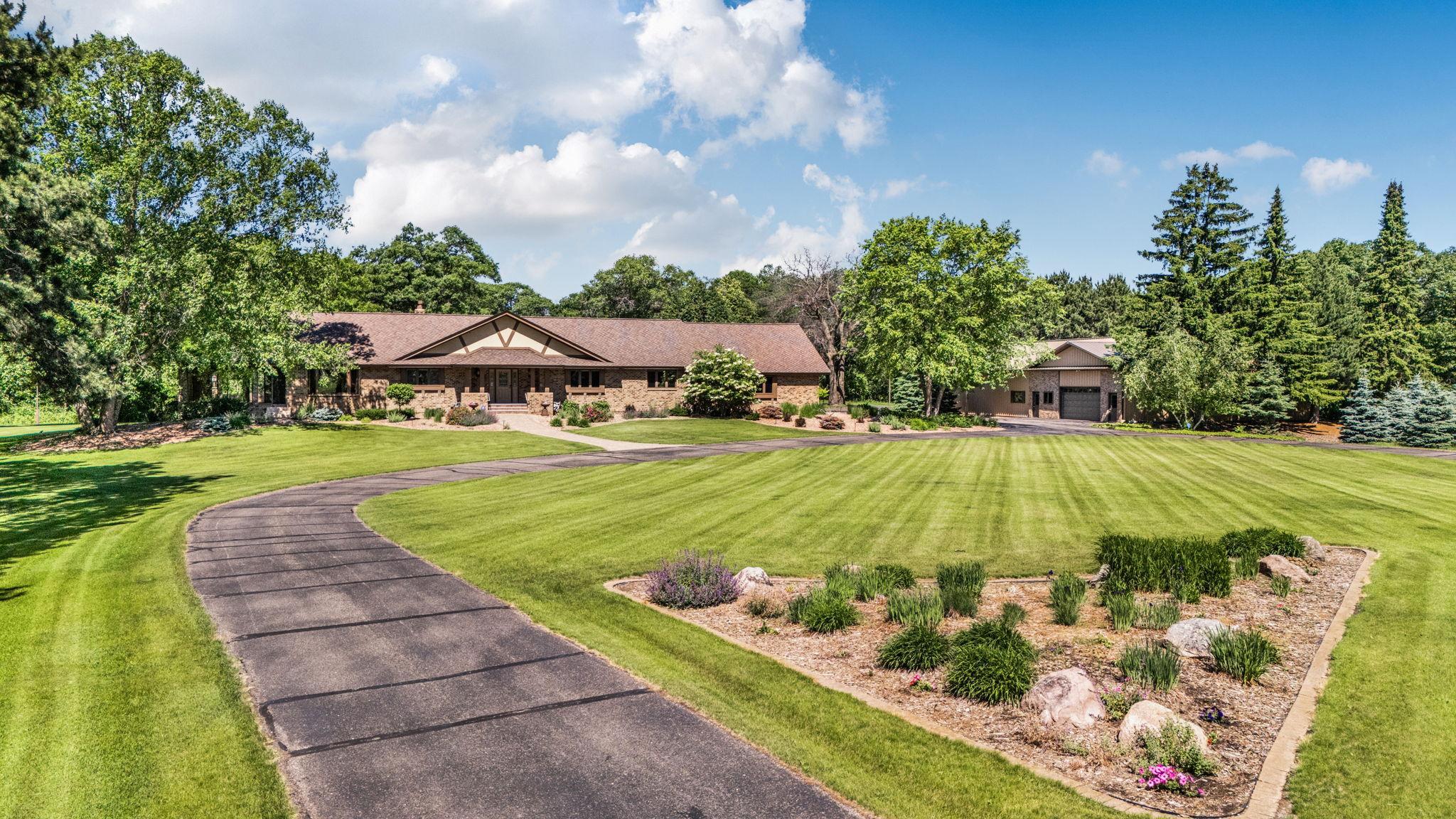 An impressive exterior featuring low-maintenance brick and stucco, 50-year shingles, cove-molded fascia, professional landscaping, underground irrigation, three patios, LED landscape lighting, and mature trees for endless privacy.