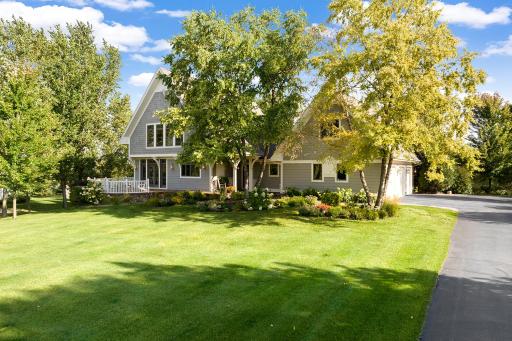 Fabulous curb appeal! Home is set away from the road, across an expansive, manicured front yard and boasts a side-entry garage design, enabling the lovely perennial gardens, curved patio & covered front porch to take center stage.