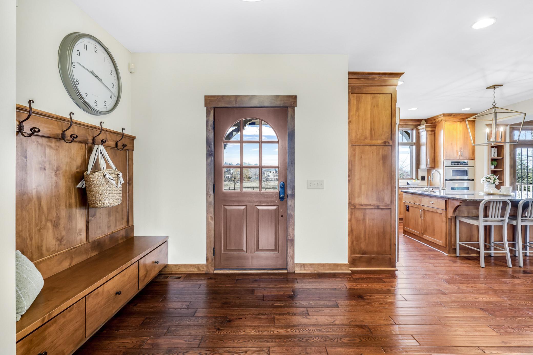Refinished front door (2025) with glass insert + custom built-in lockers with hooks, bench & storage…down the hall is a complementary refinished door which leads to the backyard deck.