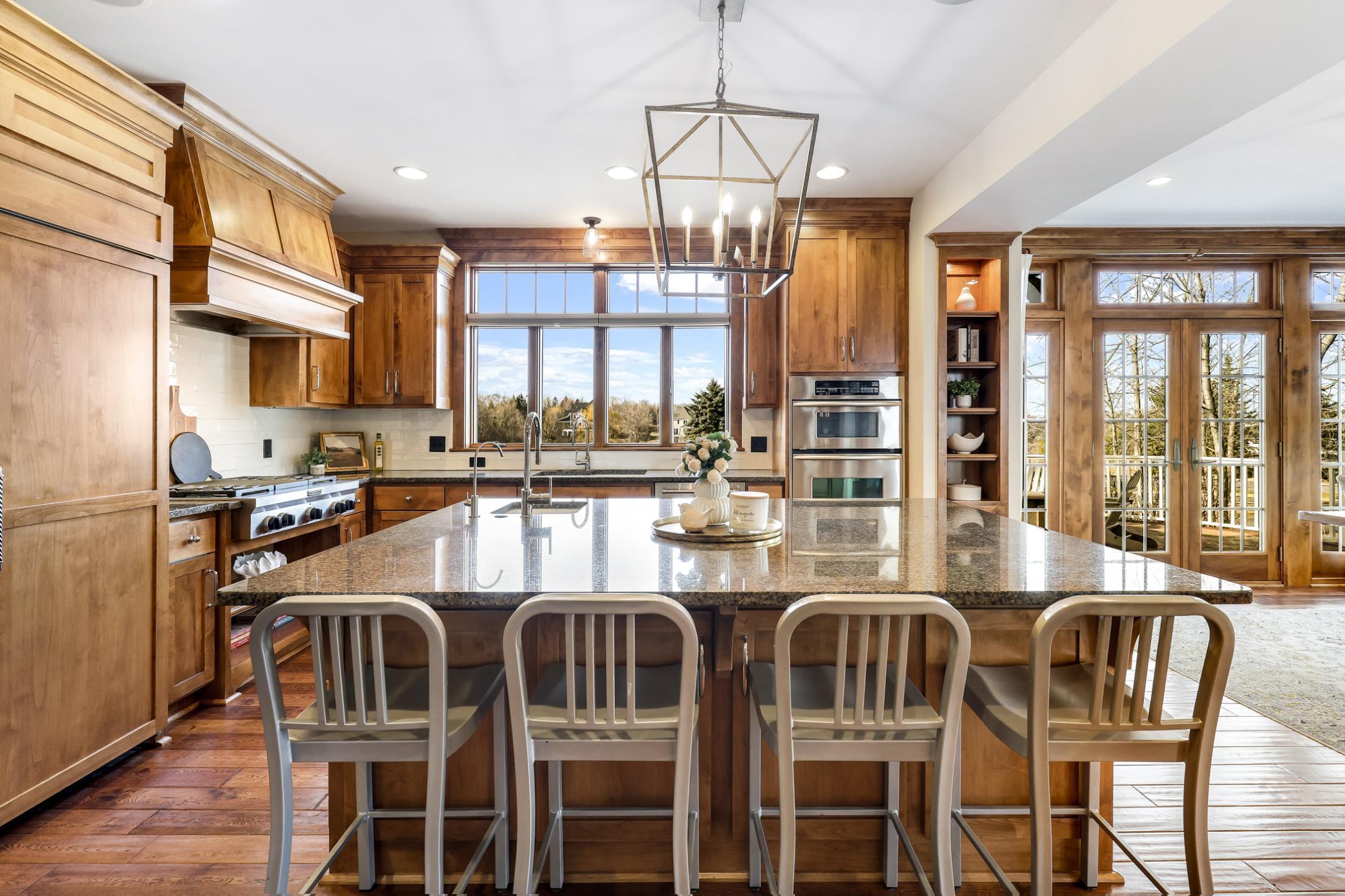 Custom cabinetry with crown molding tops, complementary wainscoted hood above the gas cooktop, a fantastic mix of cabinets, drawers, and shelves.