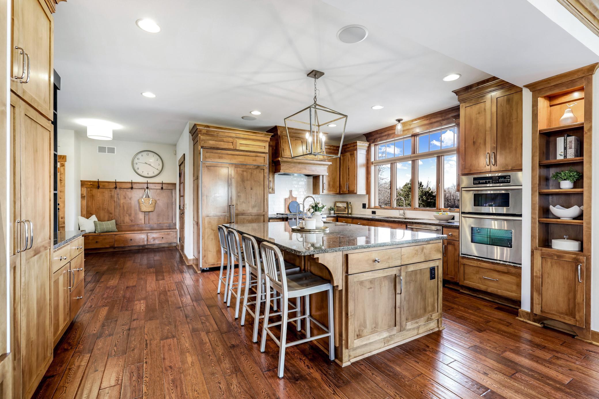Large island with granite countertops, breakfast bar seating, prep sink, and a ton of storage. Refrigerator with custom panels to match cabinets.