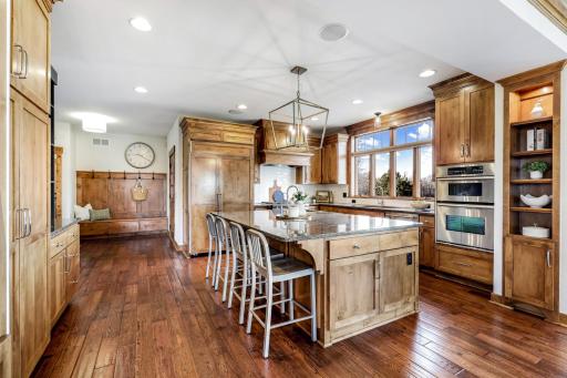 Large island with granite countertops, breakfast bar seating, prep sink, and a ton of storage. Refrigerator with custom panels to match cabinets.