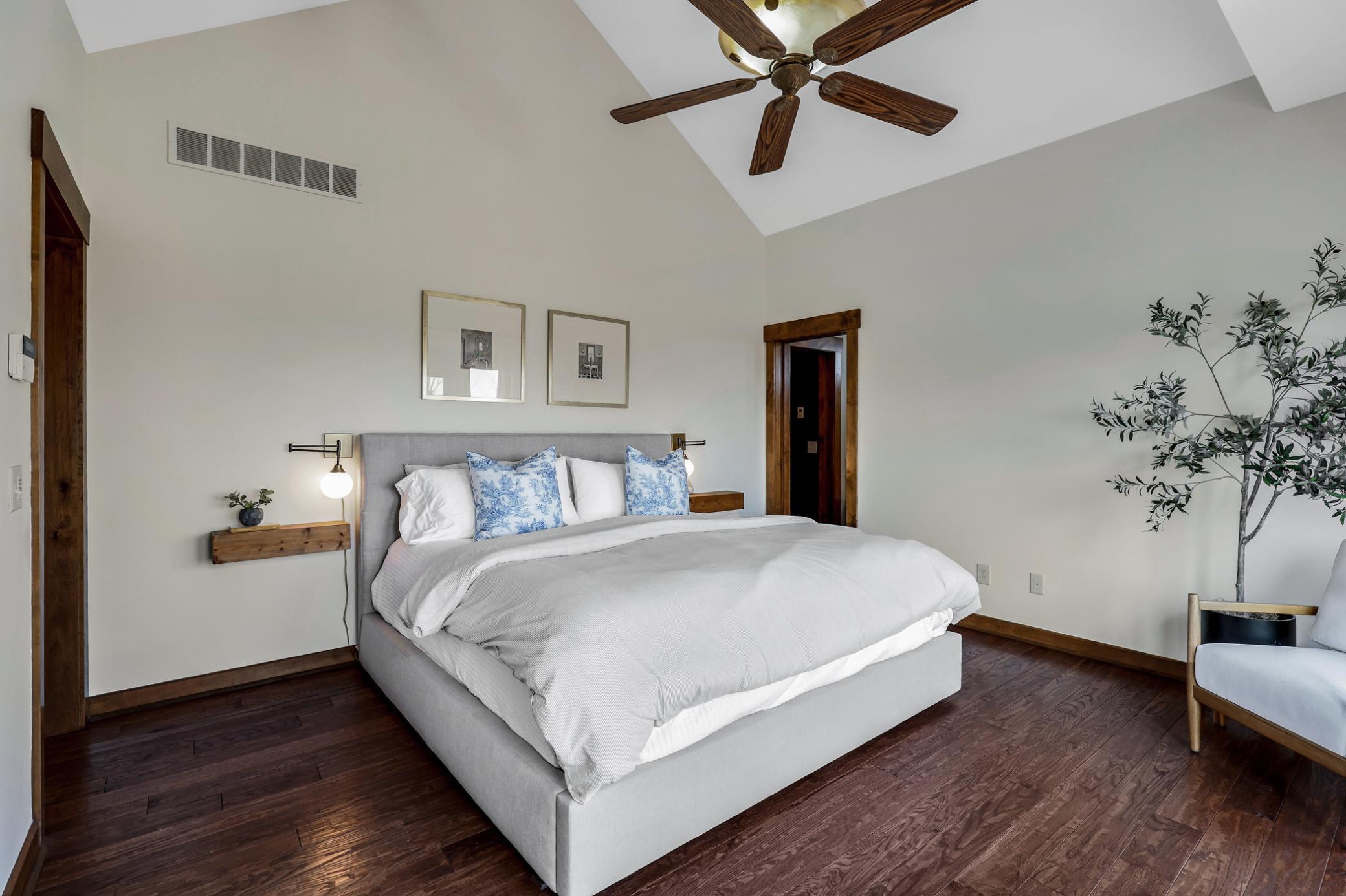 Spacious sleeping area with soaring vaulted ceilings and updated hardwood floors (2020). Wake up to morning light steaming through the sliding doors.
