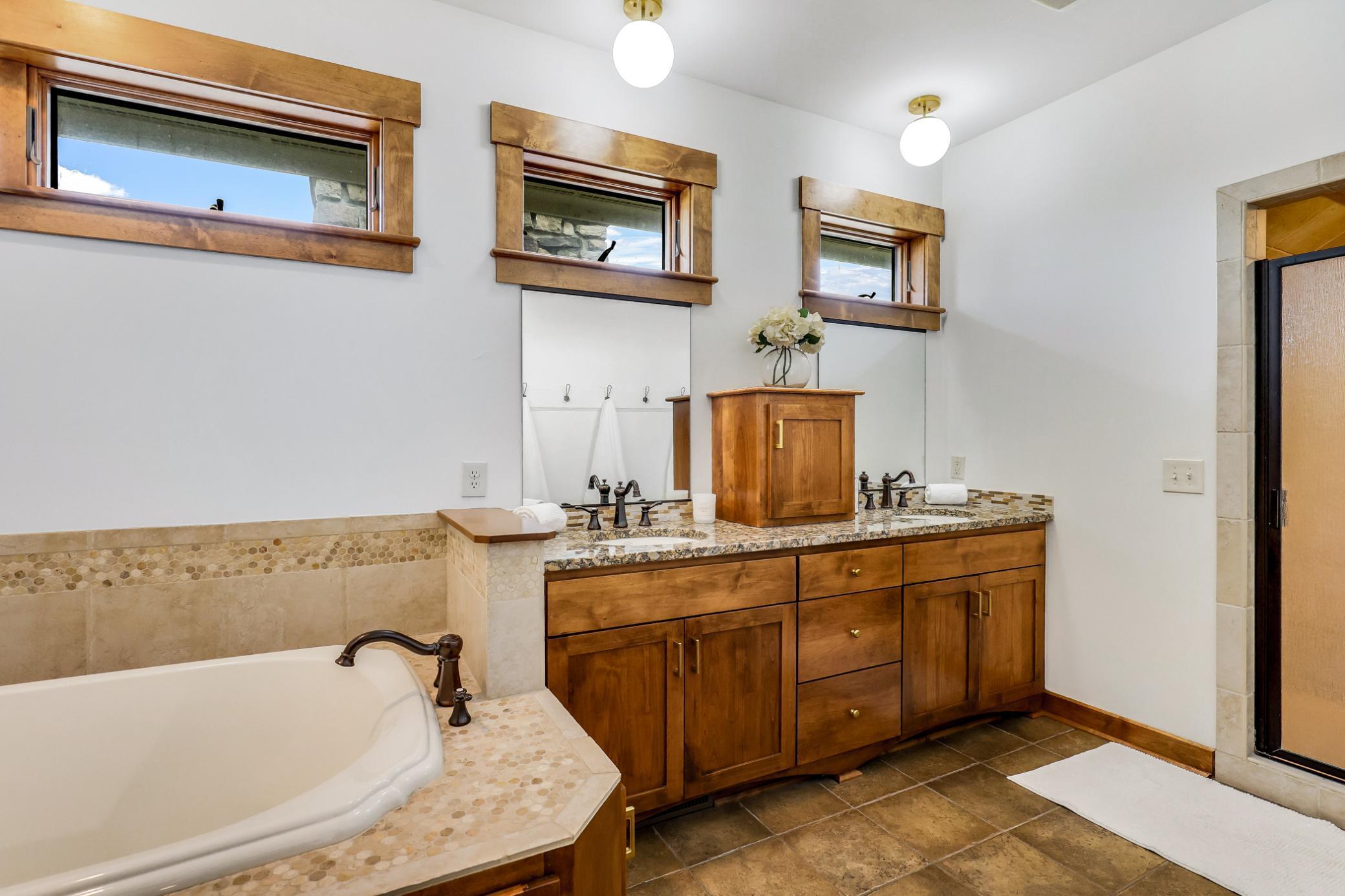 Large vanity with dual sinks and granite countertops + a soaking tub.