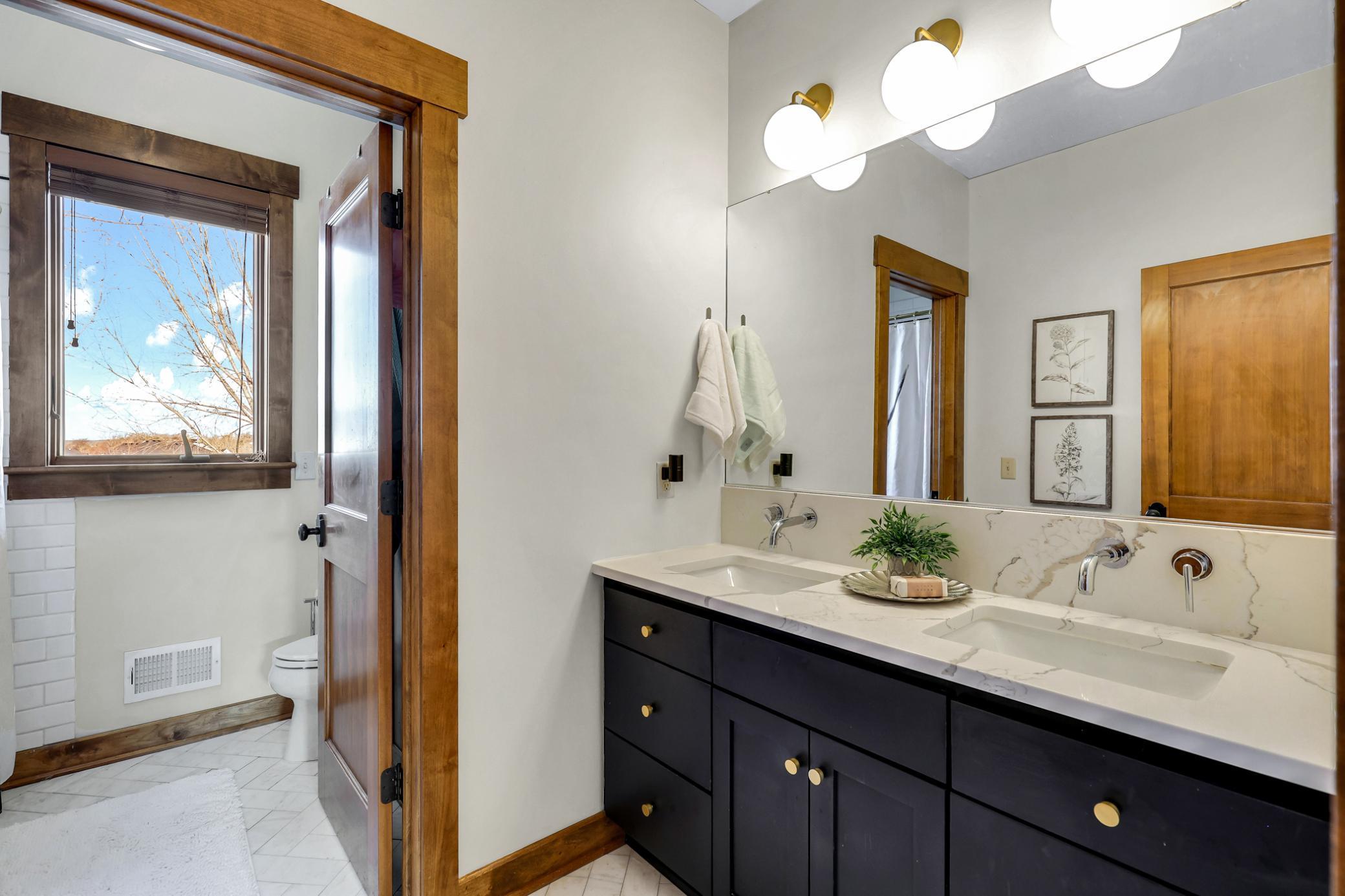 Full bath nearby in the hallway (updated in 2019) with dual sinks, quartz countertops and a privacy door which leads to the toilet and bath/shower with subway tile surround.