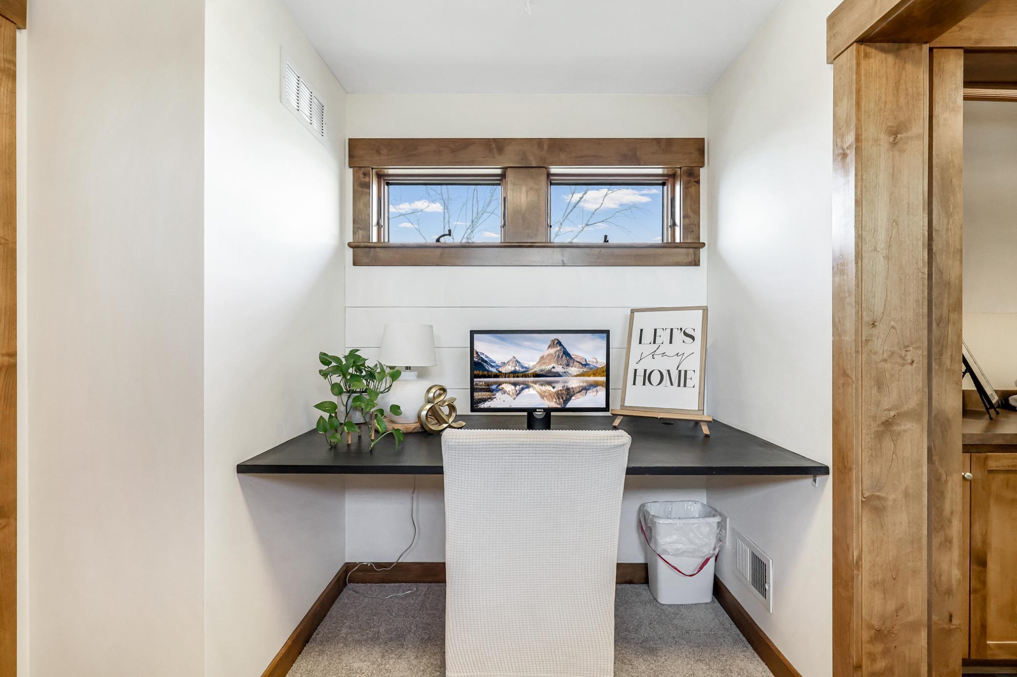 A cozy galley niche adjoining the laundry room with transom windows on both sides of the room, built-in desk with ship lap accent wall and door which leads to the east wing of the home.
