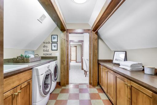 Accessed via a pocket door near the primary suite, its open galley design features washer, dryer, sink & counter on one side, while the other offers storage, folding counter & drying rack.