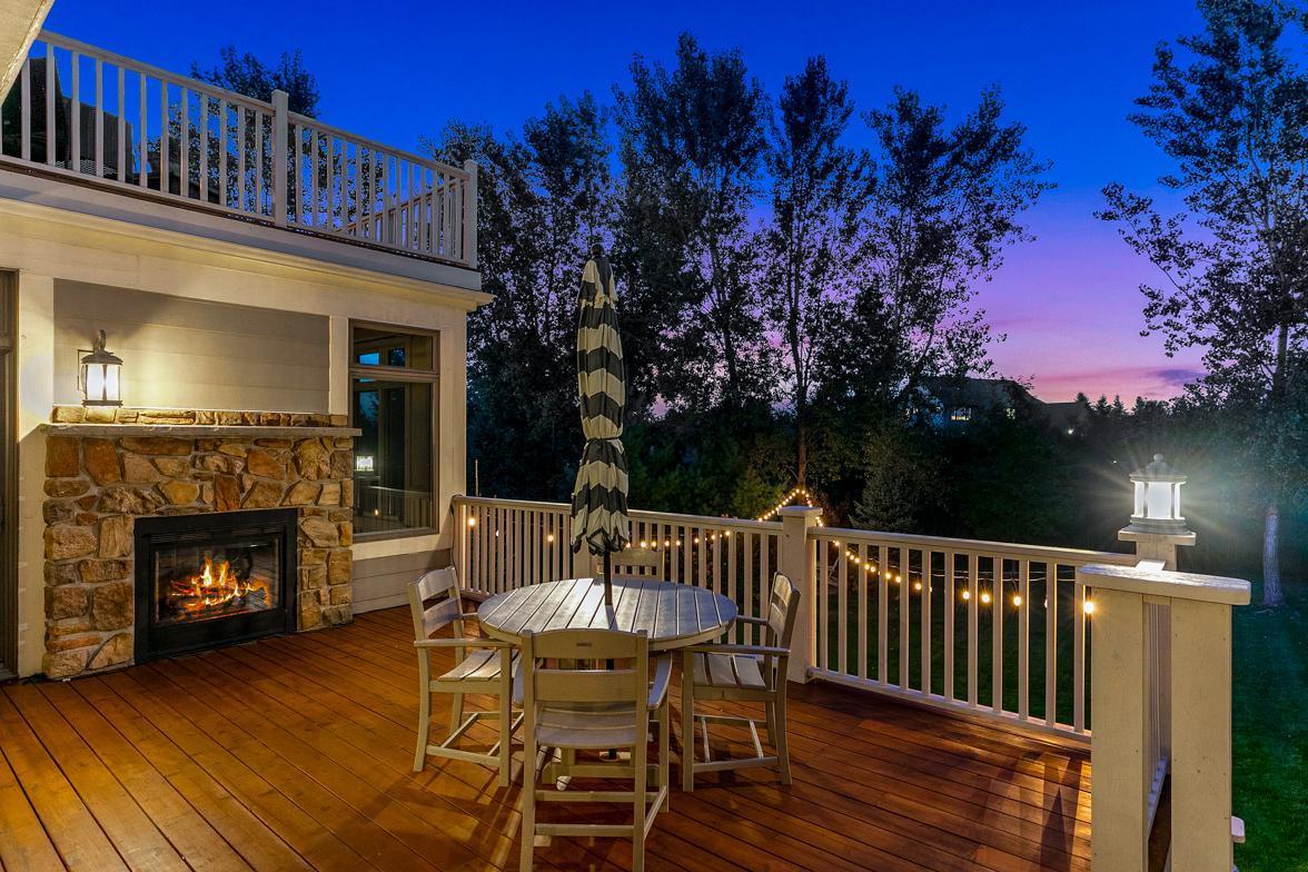 Relaxing backyard deck featuring a 2-sided gas fireplace with stone surround (shared with the 4-season porch).