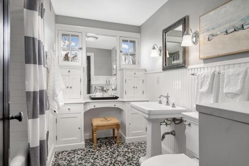 Charming kids bathroom has herringbone floor tile, newer beadboard wainscoting and newer subway tile.