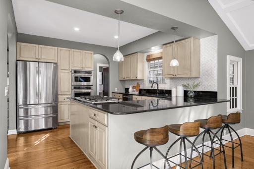 The kitchen features stainless steel appliances, granite countertops and a large peninsula with breakfast bar