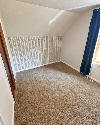 Bright second bedroom with newer carpeting, natural light and charming architectural character.