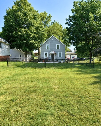 A fully fenced front yard offers plenty of usable green space, all beneath mature shade trees.