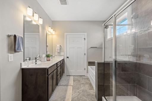 Spa-like primary bath offers a tile walk-in shower and separate soaking tub