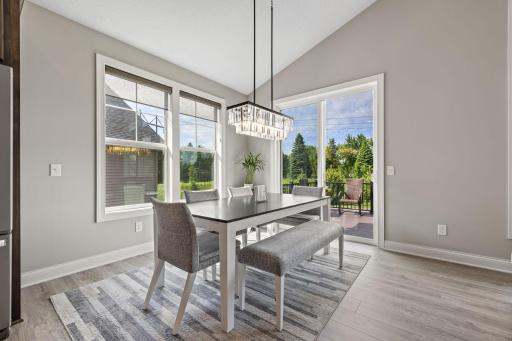Sunlit dining room accented by a beautiful chandelier and convenient deck access, creating the perfect setup for indoor-outdoor dining and grilling