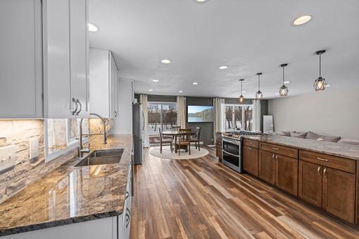 Gorgeous kitchen has been remodeled and includes stainless appliances, a gas range, granite counter, white cabinetry & a stone backsplash