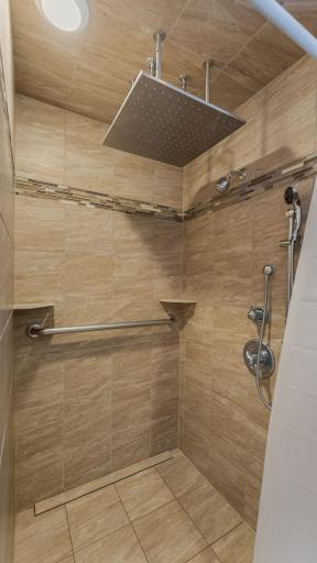 Luxurious tiled shower featuring overhead rain shower and secondary showerhead.