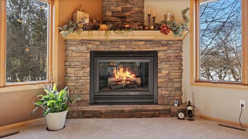 Bricked in fireplace is a focal point of the front living room, convenient gas fireplace bookended with windows and natural landscape backdrop.
